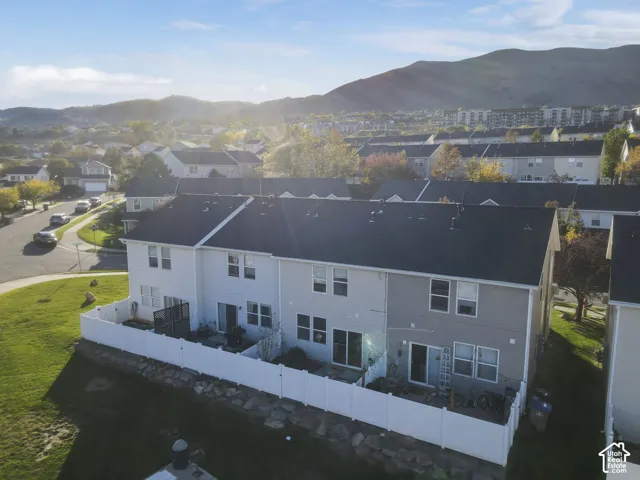 Aerial perspective featuring multi-story residences with horizontal siding, dark-toned shingled roofs, private fenced rear patios, and a mountainous backdrop