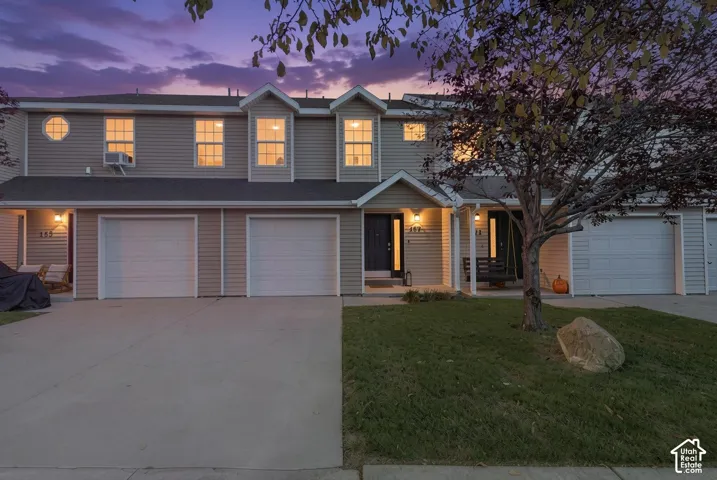 Multi-level townhouse exterior featuring vinyl siding, decorative gables, attached single-car garages, and concrete driveways