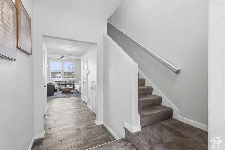 Entryway featuring wood-finish tile flooring, carpeted staircase, and a white handrail