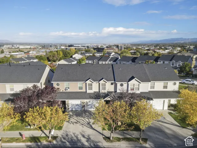 Multi-level residential exterior featuring dark shingle roofing, light-toned siding, gabled roof peaks, and attached garage bays