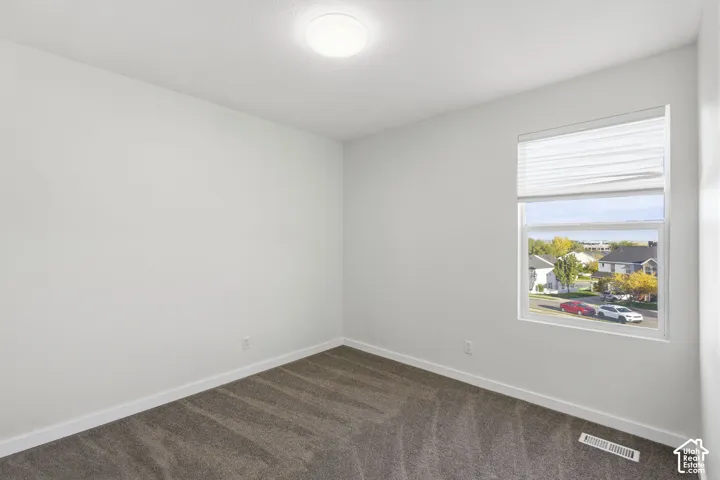 Neutral wall tones, wall-to-wall carpeting, window with a horizontal blind, and a flush-mount ceiling light fixture
