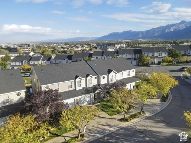 Multi-level residential building featuring a shingled roof, attached garages, stone and siding exterior, and mountain scenery