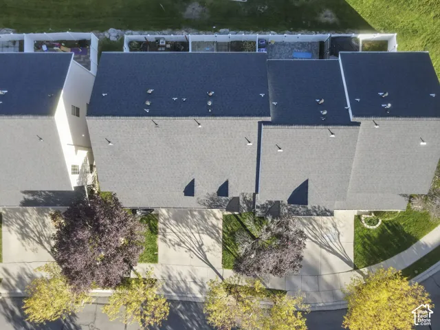 Aerial view of a multi-unit property featuring asphalt shingle roofing, concrete driveways, paved street access, and mature deciduous trees