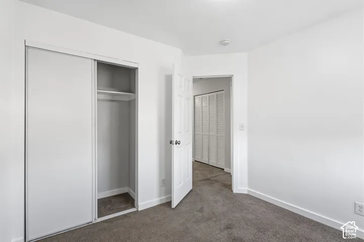 Interior room featuring neutral carpeting, a built-in sliding door closet with overhead shelving, and a six-panel swing door
