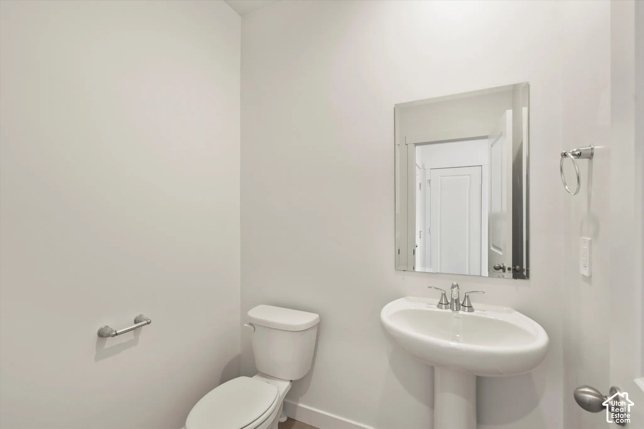 **Disclaimer** Interior package & colors may vary.  Powder room featuring a white pedestal sink, polished chrome faucet, wall-mounted mirror, and metal hardware