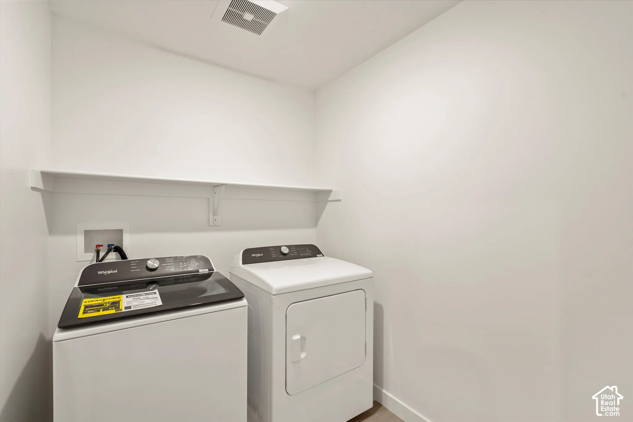 Utility area featuring a wall-mounted shelf and recessed water hookups