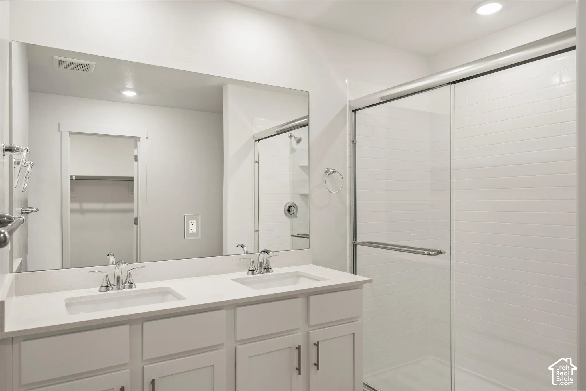 **Disclaimer** Interior package & colors may vary.  Double vanity featuring rectangular undermount sinks, stone countertops, large wall-mounted mirror, and a glass-enclosed shower with tiled surround