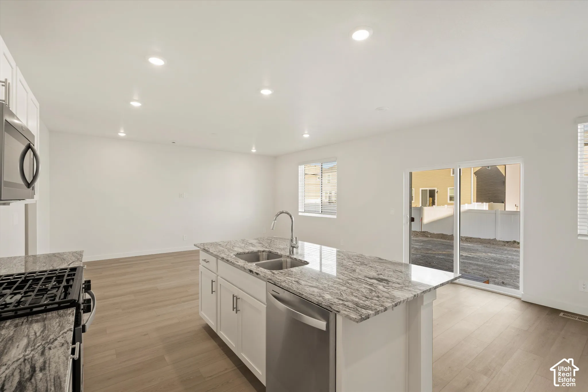 **Disclaimer** Interior package & colors may vary.  Kitchen featuring a central island with a stone countertop, white cabinetry, stainless steel appliances, recessed lighting, and wood-finish flooring