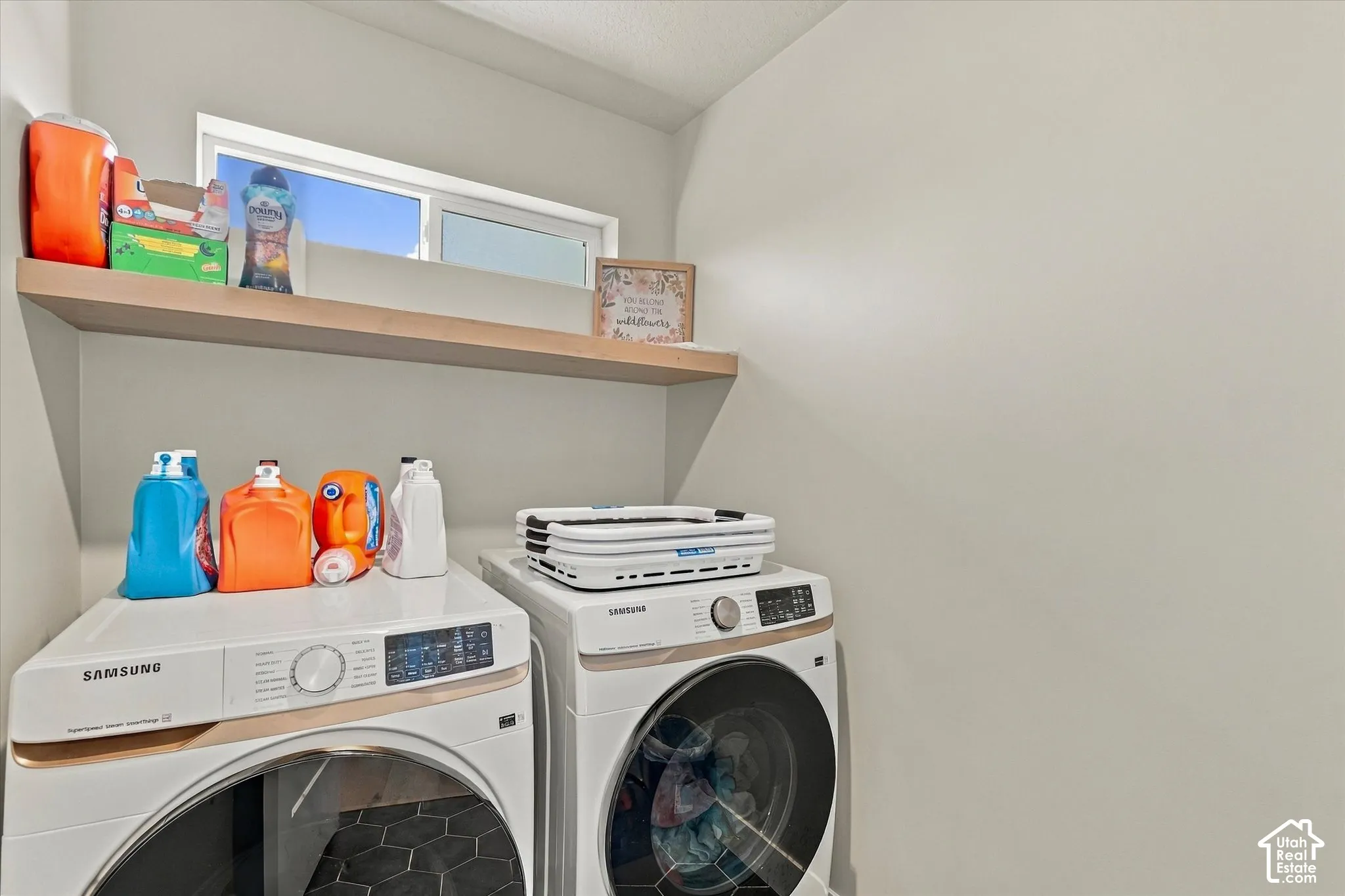 Laundry space featuring a horizontal wall-mounted floating wood shelf, hexagonal tile flooring, and a rectangular casement window