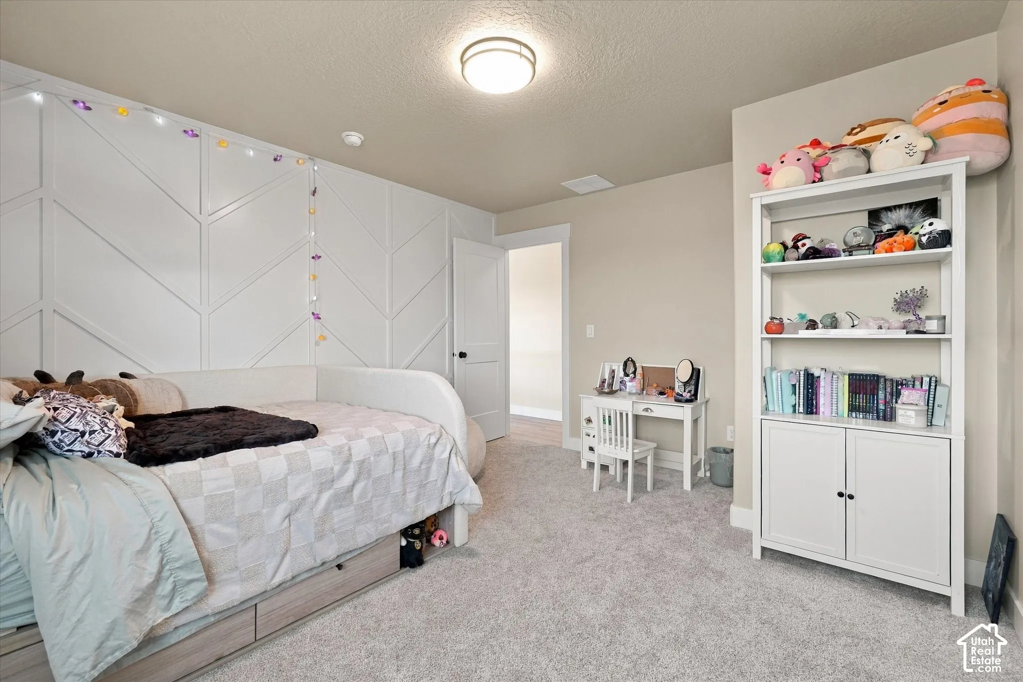 Bedroom featuring a white herringbone-patterned accent wall, neutral carpeting, and a flush-mount ceiling light fixture