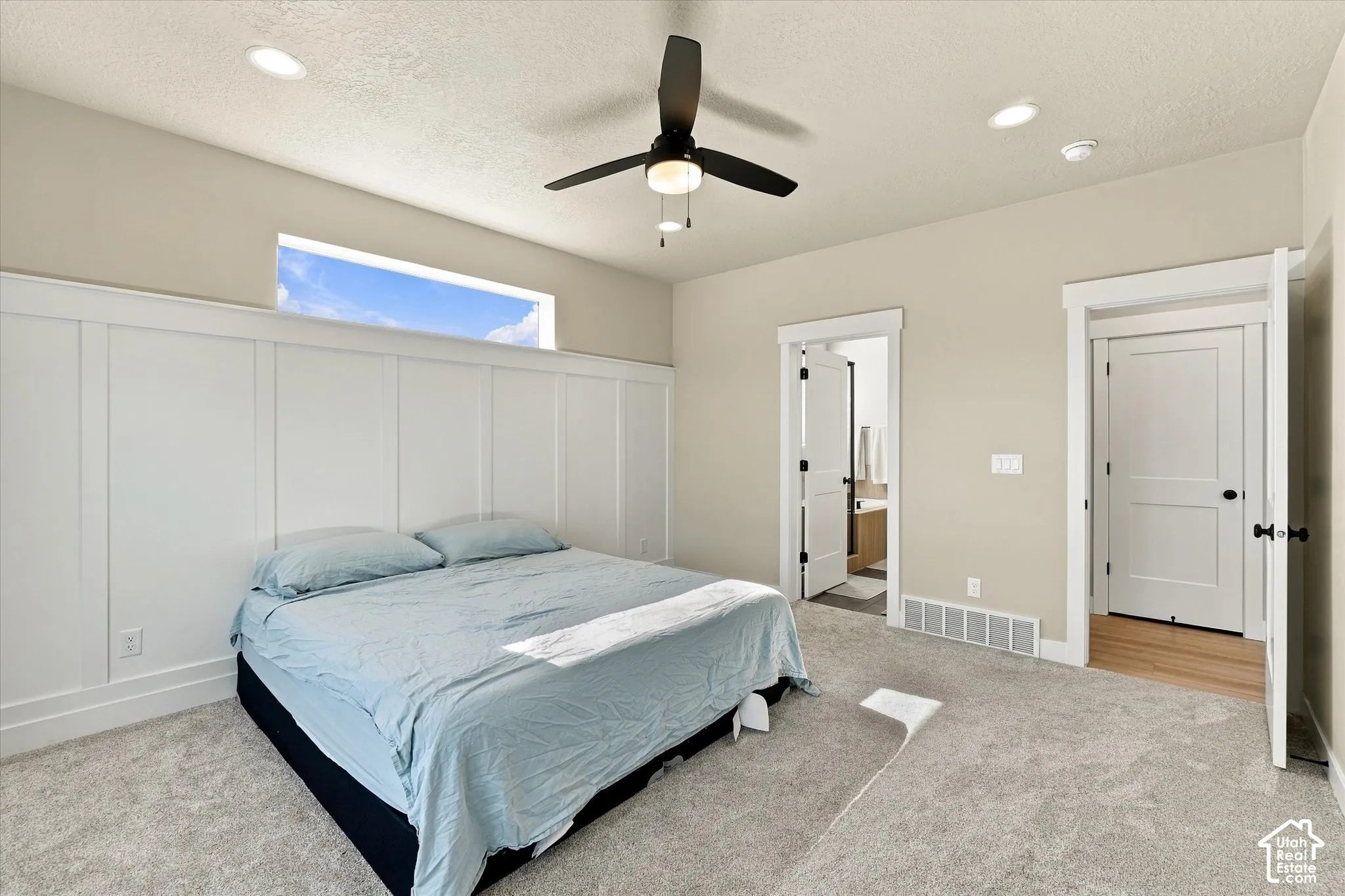 Interior space featuring white board-and-batten wall detailing, horizontal transom window, recessed ceiling lighting, and a multi-blade ceiling fan with integrated lighting