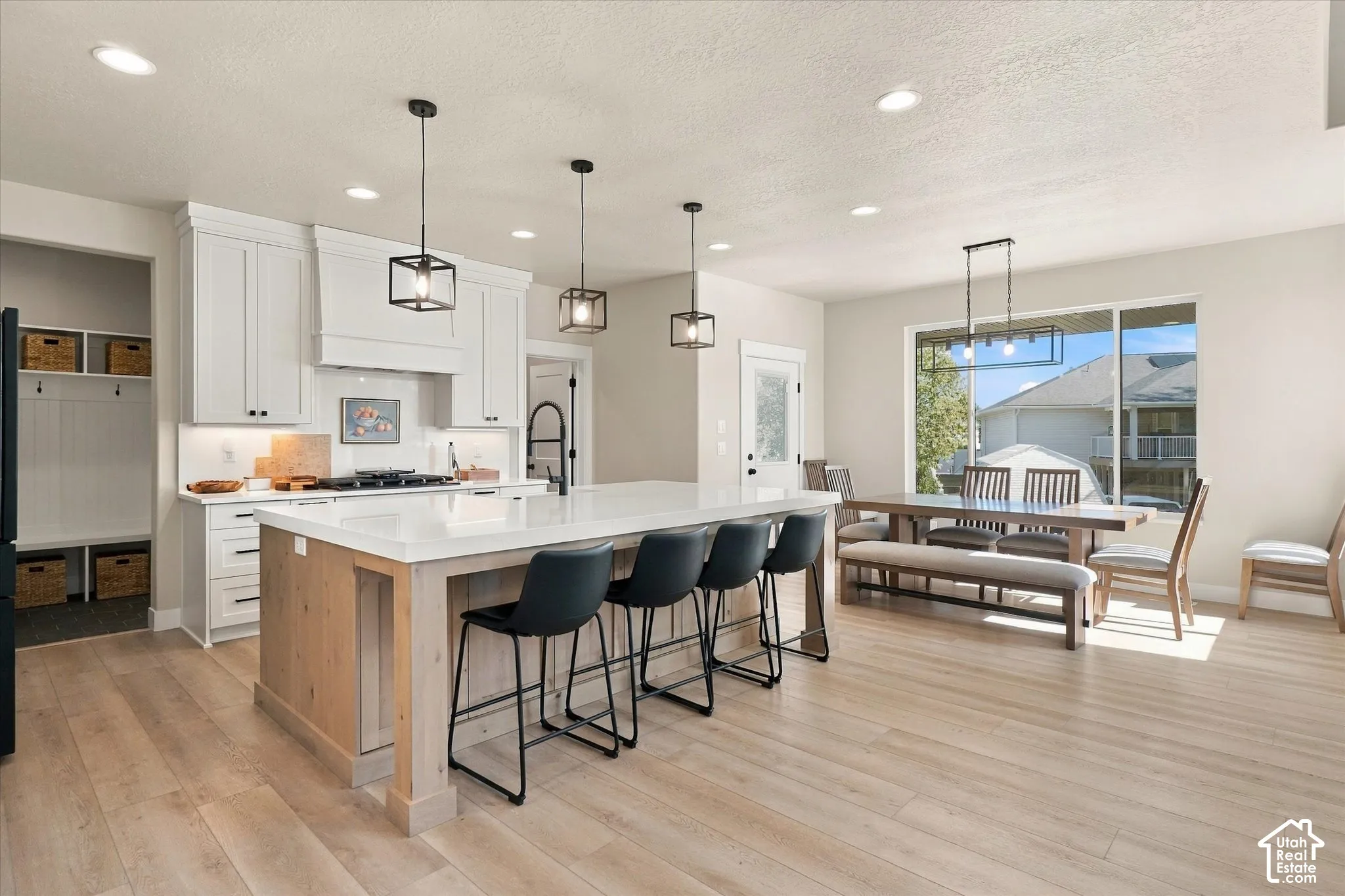Kitchen featuring a large central island with quartz countertops, custom white cabinetry, wood-finish flooring, recessed lighting, and geometric pendant fixtures