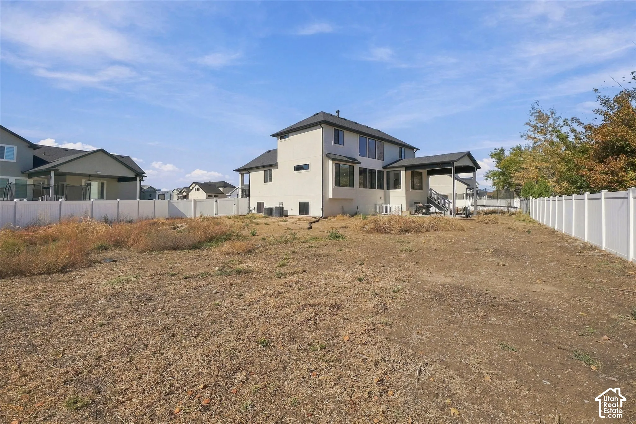 Expansive lot featuring a full-perimeter white vinyl fence and a rear covered patio