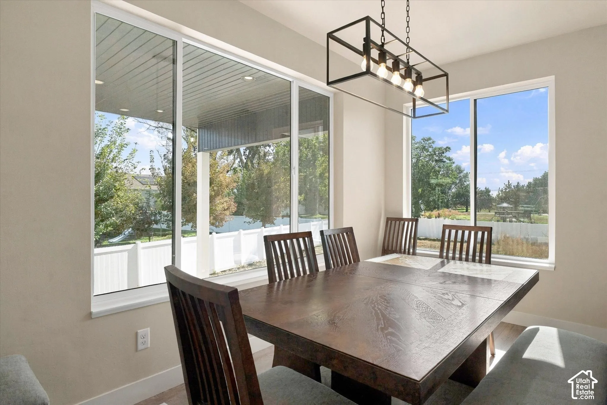 Large windows with white frames, matte black open-frame linear light fixture, and neutral-toned wall finish