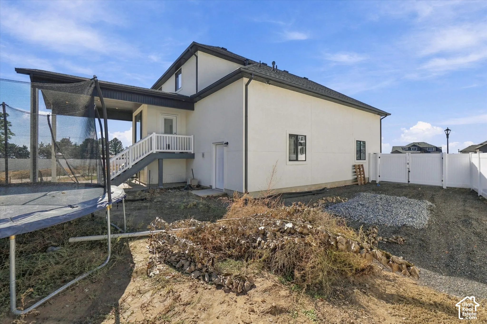 Exterior featuring a covered deck with white railing, light-toned siding, and a white privacy fence enclosing the perimeter