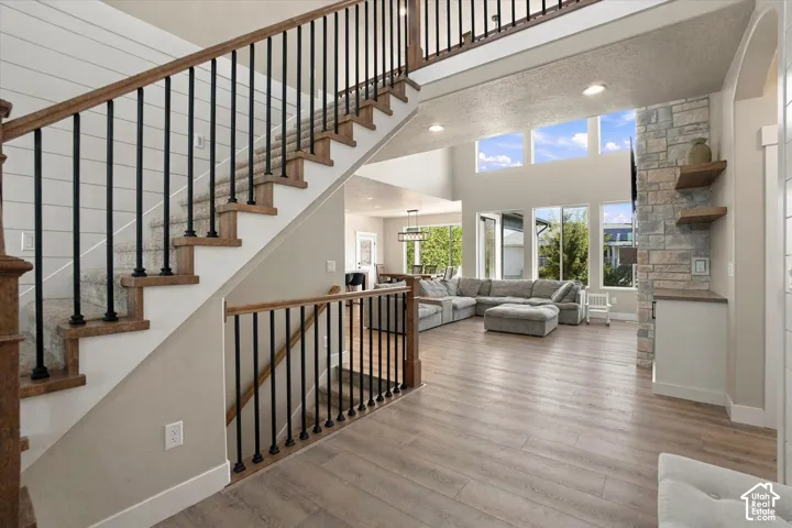 Staircase featuring wood treads and black metal balusters, shiplap wall accent, floor-to-ceiling stone fireplace surround, custom built-in shelving, and wood-finish flooring