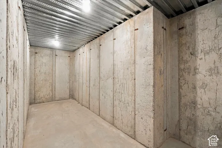 Unfinished concrete foundation walls and floor featuring exposed corrugated metal ceiling decking and overhead lighting fixtures