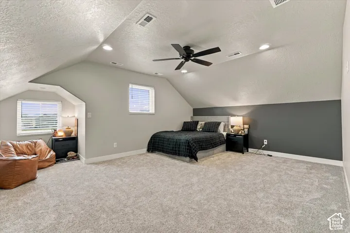 Vaulted ceilings featuring recessed lighting and a central ceiling fan, neutral wall tones with a dark accent wall, and dual windows