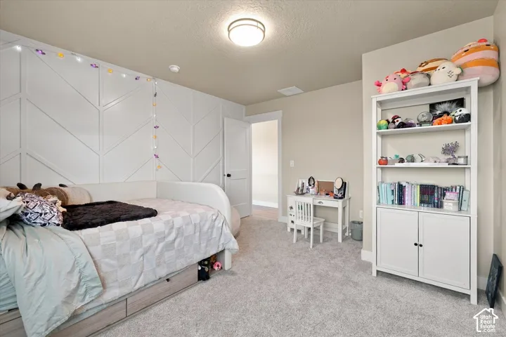 Bedroom featuring a white herringbone-patterned accent wall, neutral carpeting, and a flush-mount ceiling light fixture