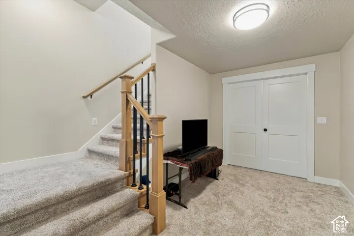 Staircase featuring carpeted steps, a wooden handrail, and black metal balusters, paired with white double doors featuring casing trim and a circular flush-mount ceiling light