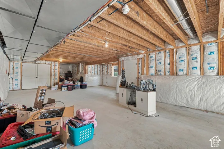 Unfinished lower level featuring exposed wood joist ceilings, concrete flooring, insulated wall paneling, and an exposed ventilation duct system