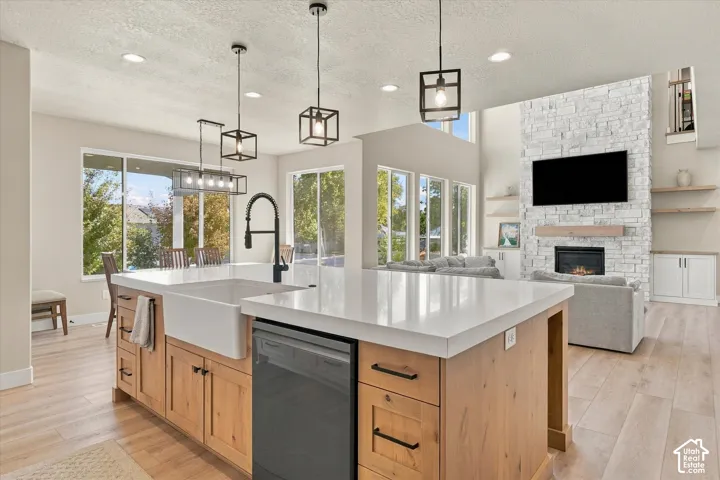Kitchen island featuring a white apron-front sink, quartz countertop, and light wood-finish cabinetry with matte black hardware