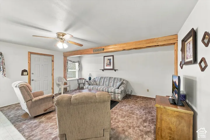 Exposed timber support beam, wall-to-wall carpeting, wood-trimmed door frame, and ceiling-mounted fan with integrated lighting