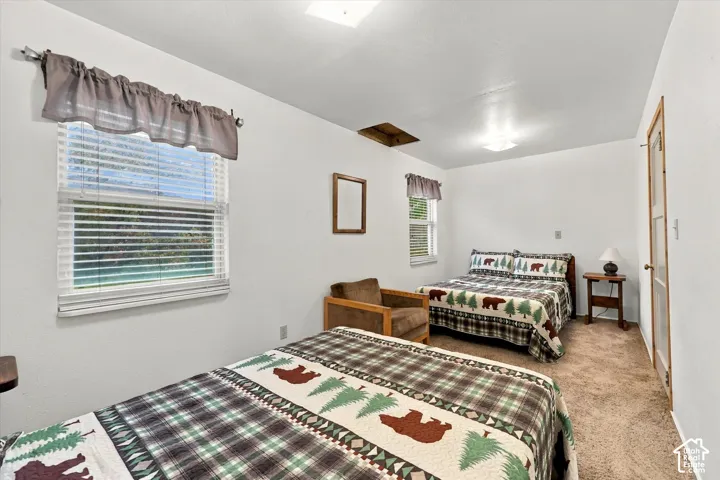 Neutral interior featuring crisp white walls, neutral carpeting, and two dual-pane windows with horizontal blinds