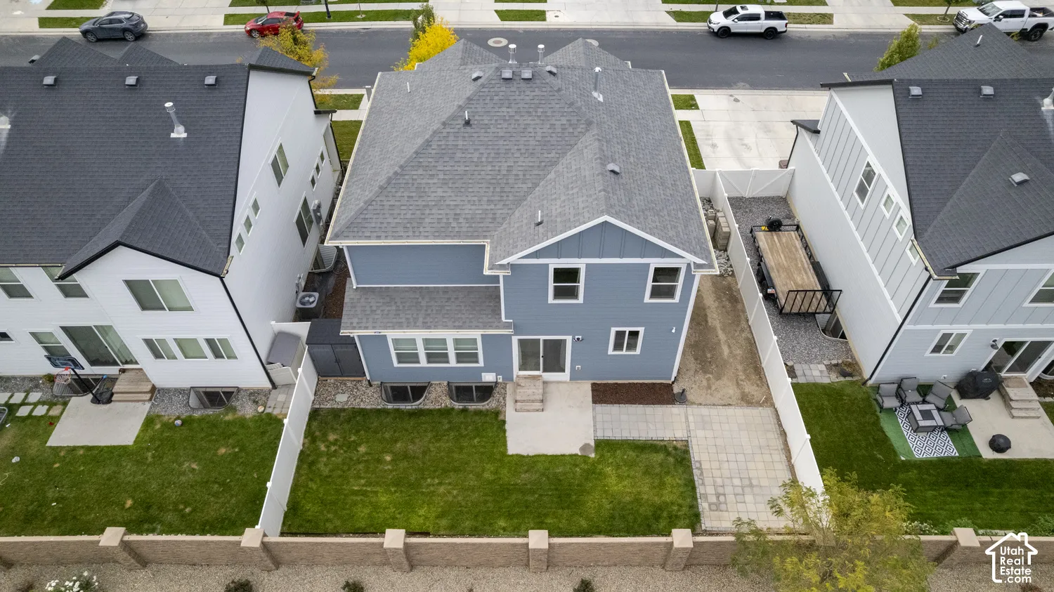Two-story home with a multi-textured exterior, asphalt shingle roof, rear concrete patio, fully enclosed perimeter fencing, and a grass lawn