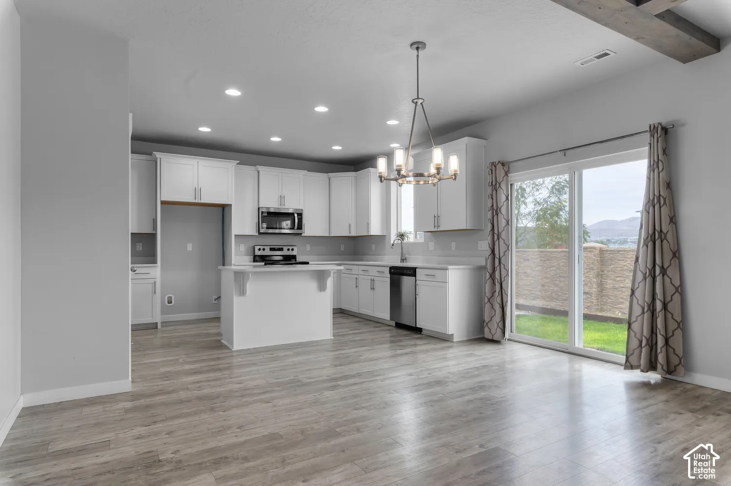 Kitchen featuring white cabinetry, wood-finish flooring, recessed lighting, a stainless steel appliance suite, and a sliding glass door