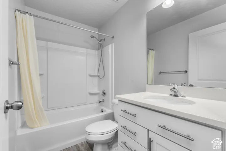 Bathroom featuring a white vanity with a composite countertop, undermount sink, integrated tub and shower combination with a handheld fixture, and large wall-mounted mirror