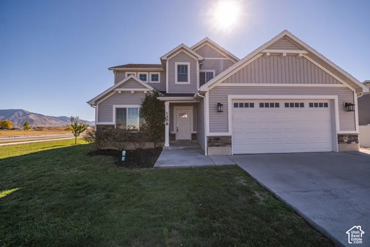 Multi-level exterior featuring horizontal lap siding, stone veneer accents, an attached two-car garage, and mountain topography