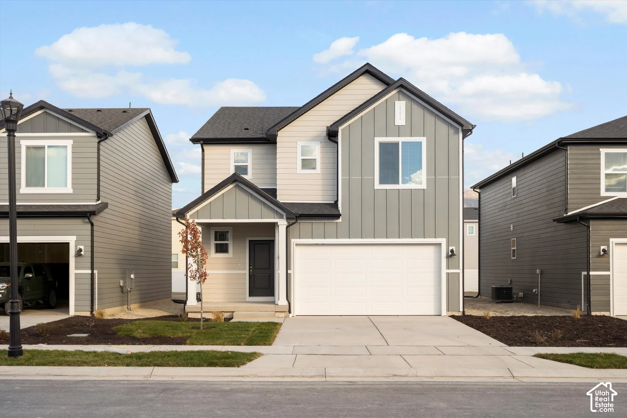 Two-story exterior featuring a mix of vertical board-and-batten and horizontal lap siding, an attached two-car garage, and a covered front entryway