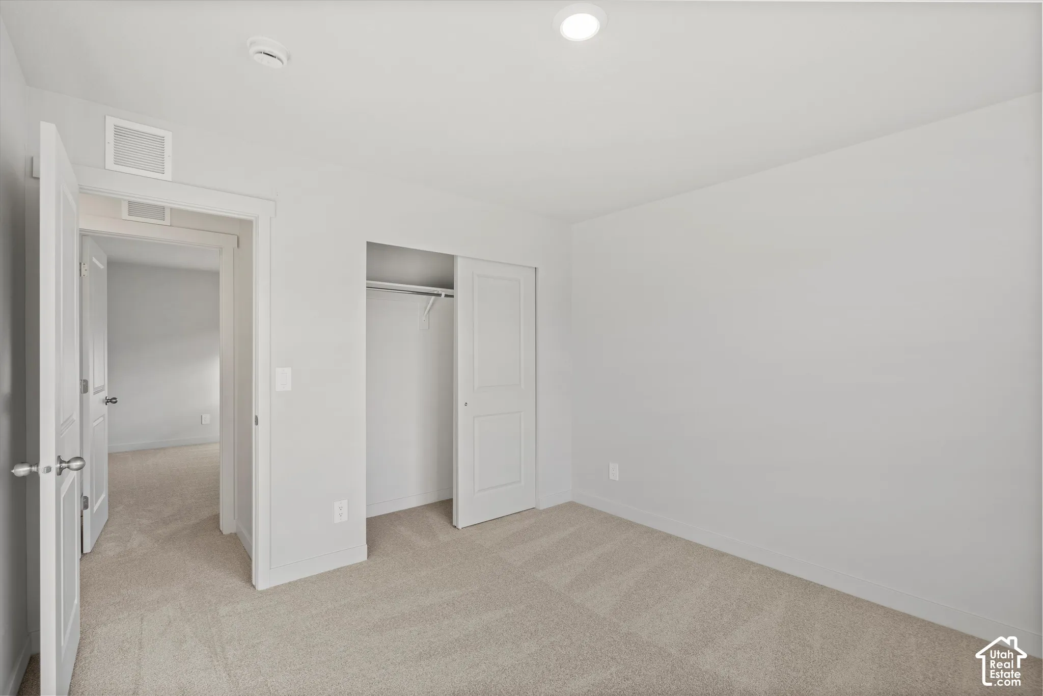 Interior room featuring neutral wall paint, wall-to-wall carpeting, recessed ceiling lighting, and a reach-in closet with sliding doors