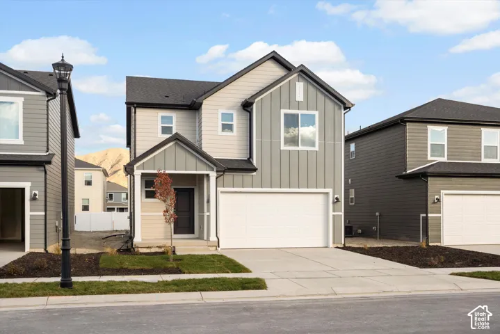 Two-story exterior featuring a mix of horizontal lap and vertical board-and-batten siding, a covered entryway, an attached two-car garage, and a concrete driveway