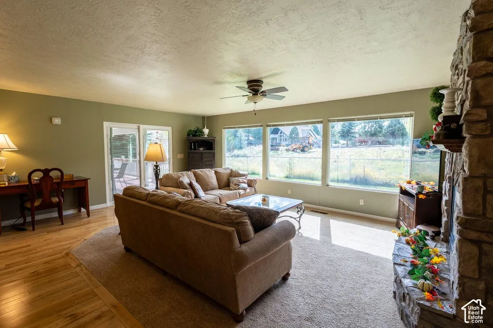 Living area featuring a floor-to-ceiling stone-faced fireplace, expansive picture windows, wood-finish flooring, and a sliding glass door