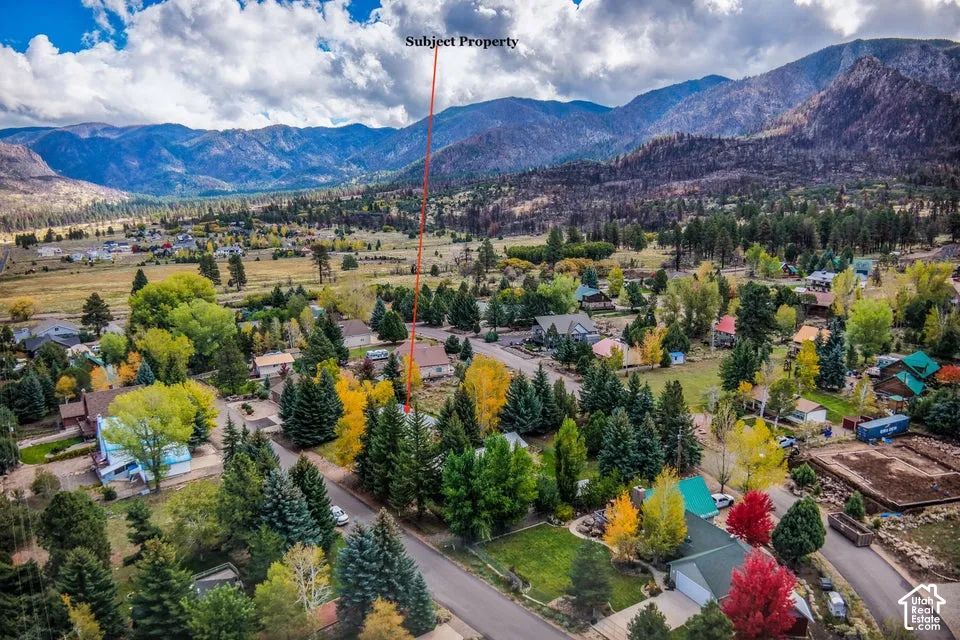 Aerial perspective featuring a residential lot situated among mature evergreen and deciduous trees with a backdrop of prominent mountain ranges