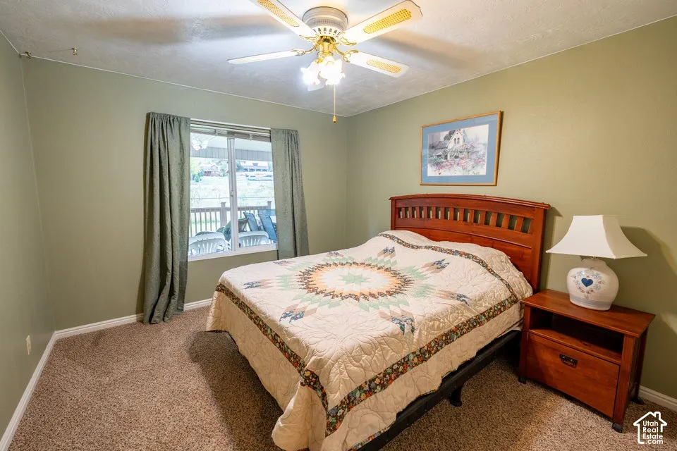 Bedroom featuring neutral-toned carpeting, a ceiling fan with integrated lighting, and a window with natural light exposure