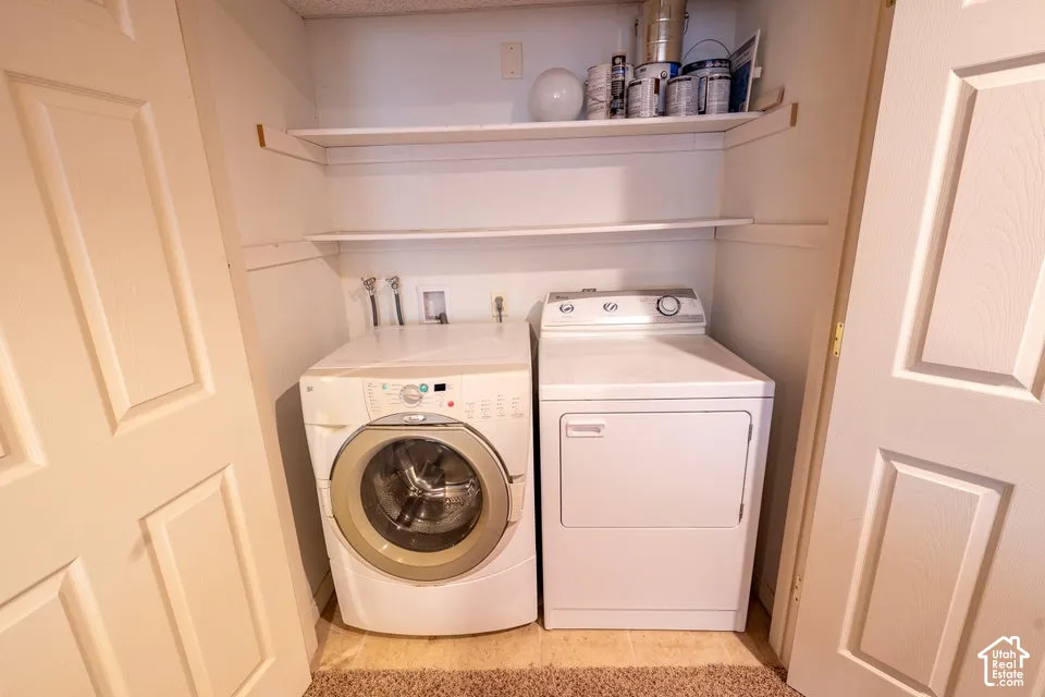 Laundry nook featuring dual-level open shelving and dedicated appliance hookups enclosed by double panel doors