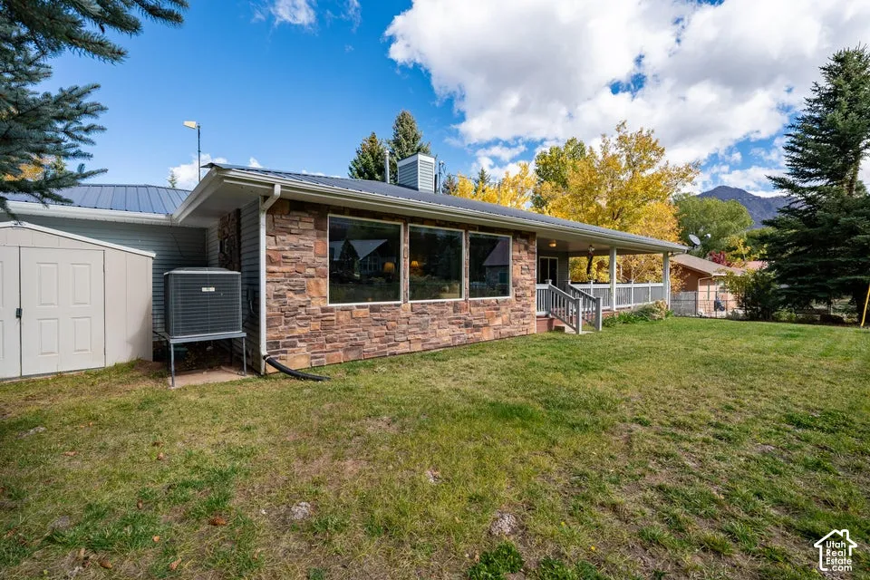Exterior featuring stone veneer siding, expansive windows, a metal roof, and a covered porch with railings