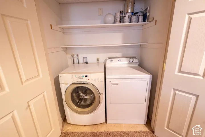 Laundry nook featuring dual-level open shelving and dedicated appliance hookups enclosed by double panel doors