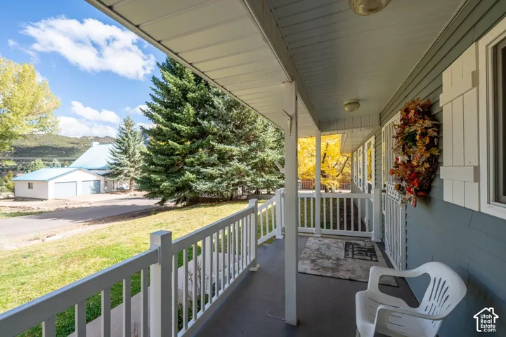 Covered front porch featuring white railing, vinyl siding, shutter accents, and mountain scenery