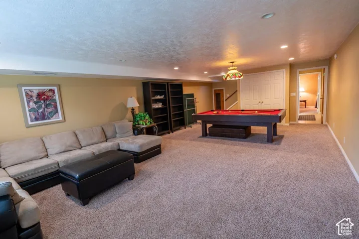 Expansive room featuring wall-to-wall carpeting, recessed ceiling lighting, a decorative hanging pendant fixture, and double-door storage closet