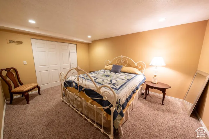 Neutral-toned room featuring textured carpeting, recessed lighting, and double-door closet cabinetry