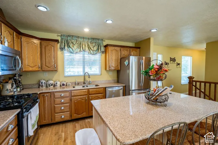 Kitchen featuring stained wood cabinetry, stone-finish countertops, stainless steel appliances, a central island, and recessed lighting