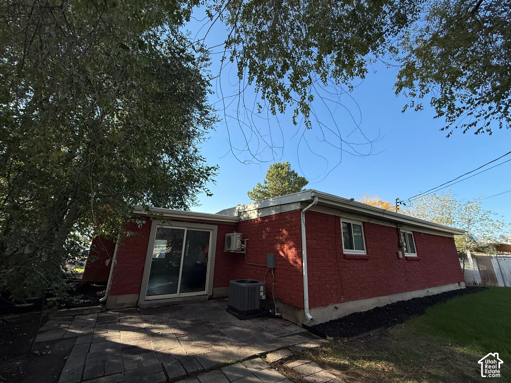 Exterior featuring red brick siding, a sliding glass door, a stone-paver patio, and an external HVAC unit
