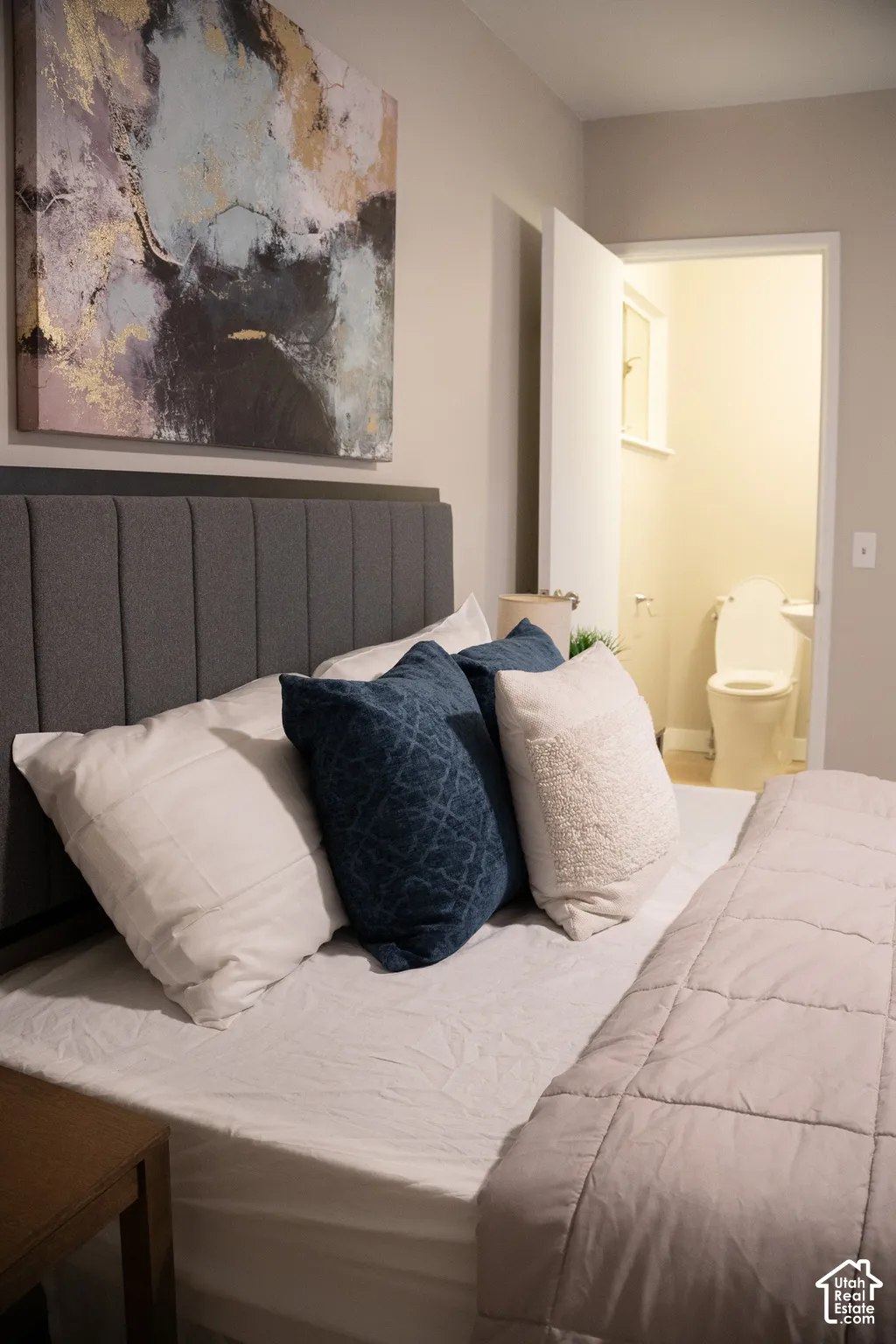 Neutral-toned walls with an integrated doorway revealing a restroom featuring a porcelain toilet and sink