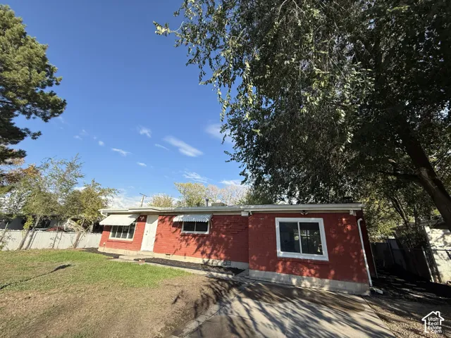 Exterior featuring red brick cladding, white-trimmed sliding windows, fixed metal window awnings, and a concrete driveway