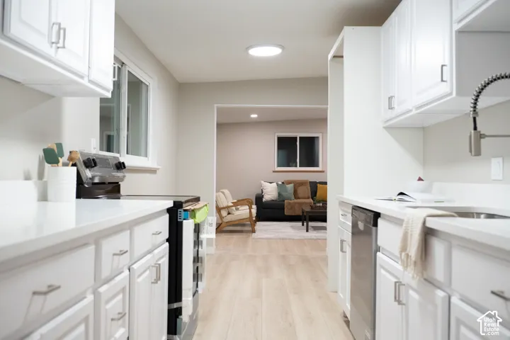 Kitchen featuring white cabinetry, solid-surface countertops, wood-finish flooring, a stainless steel dishwasher, and a gooseneck faucet