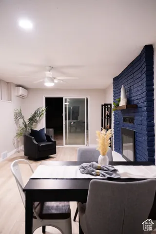 Painted brick fireplace with a wood mantel and built-in glass-door insert, light-toned wood-finish flooring, recessed lighting, ceiling fan, and sliding glass door